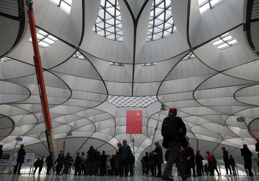 Visitors are seen under a Chinese flag at the terminal hall of the Beijing Daxing International Airport under construction, during a media tour on the outskirts of Beijing (Credit: China Daily via Reuters)