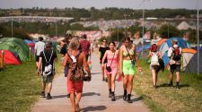Festival goers walk through a campsite during hot weather at Glastonbury Festival in Somerset