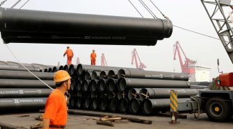 © Reuters. Workers direct a crane lifting steel pipes for export at a port in Lianyungang, Jiangsu