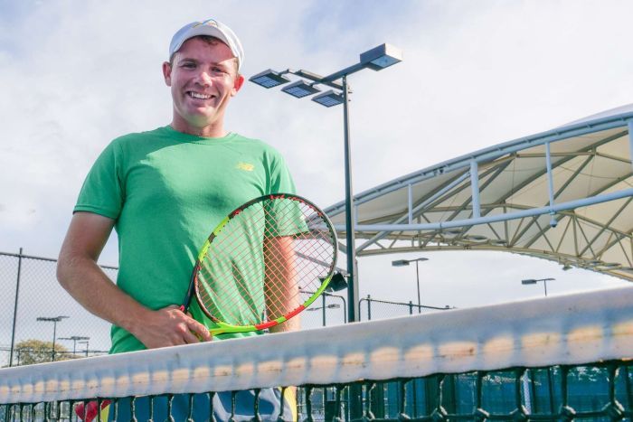 Man holds a tennis racquet on a tennis court.