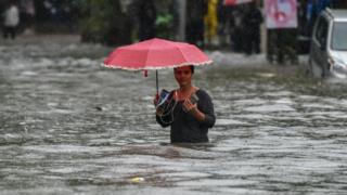 A girl walk along a flooded street after heavy rain showers Gandhi Market, Sion on July 1, 2019 in Mumbai, India. Heavy rains for last four days led to trains disruptions, flooded roads, traffic jams and flight delays.