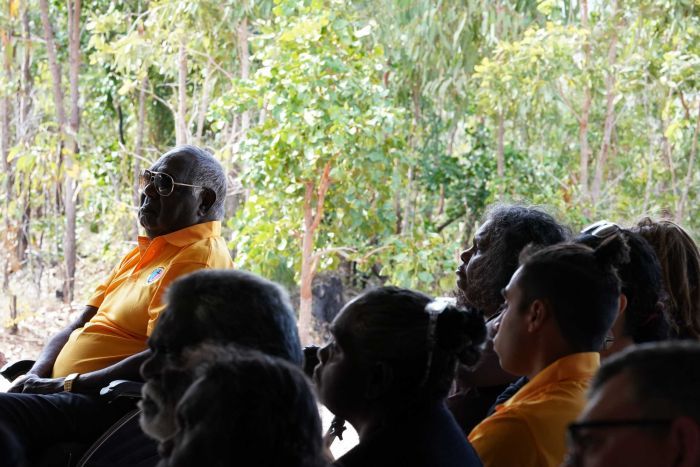 Dr Yunupingu sits in the crowd, with his grandson Michael out of focus in the foreground.