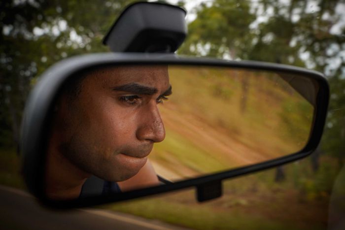 Michael is reflected in the rear view mirror of the ute he is driving.