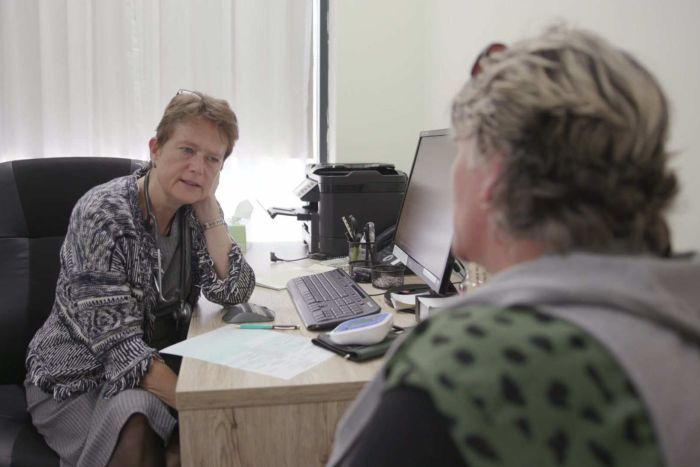 Dr Kate Shapland sitting at her desk in her surgery consulting with an unidentified patient