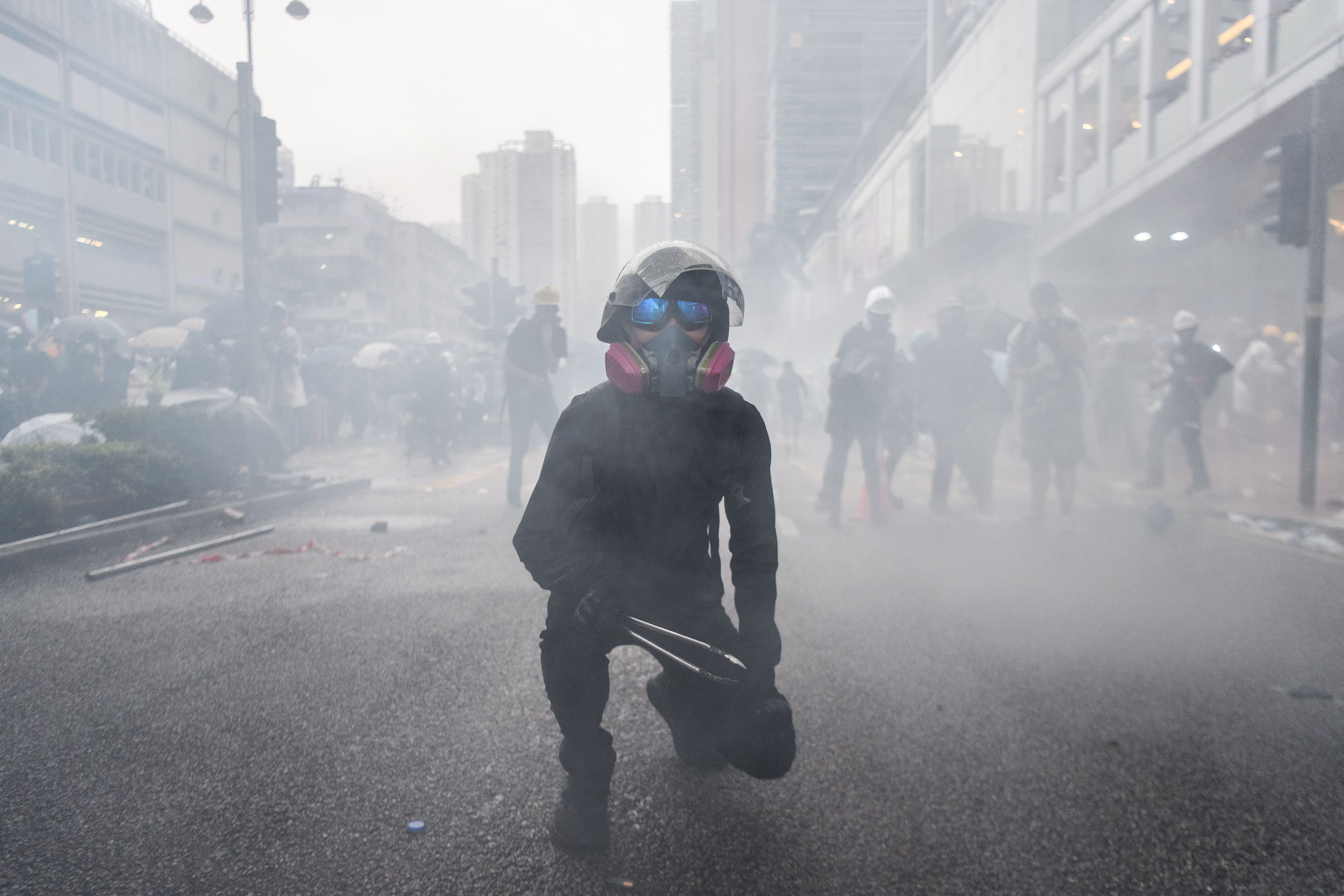 A protester holds metal cooking tongs as police fire tear gas rounds during a protest in Tsuen Wan on August 25, 2019.