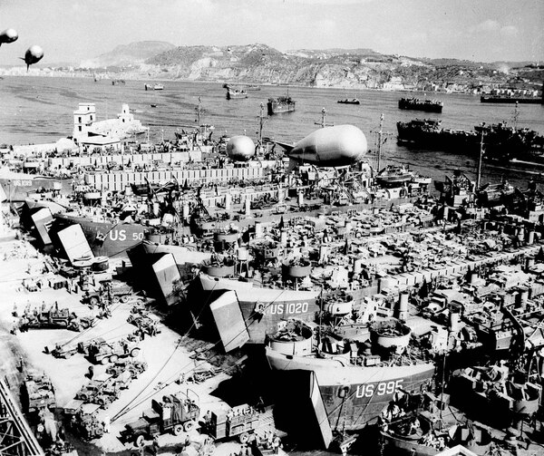 In this Aug.15, 1944 file photo, barrage balloons hover overhead as a line of WW II landing ship tanks are loaded with vehicles and supplies in a southern Italian harbor. (AP)