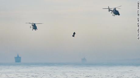 Franky Zapata stands on his jet-powered &quot;flyboard&quot; next to helicopters as he arrives at St. Margaret&#39;s Bay in Dover.