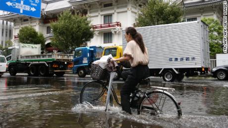 A woman cycles through a flooded area in Tokyo on September 9, 2019. 