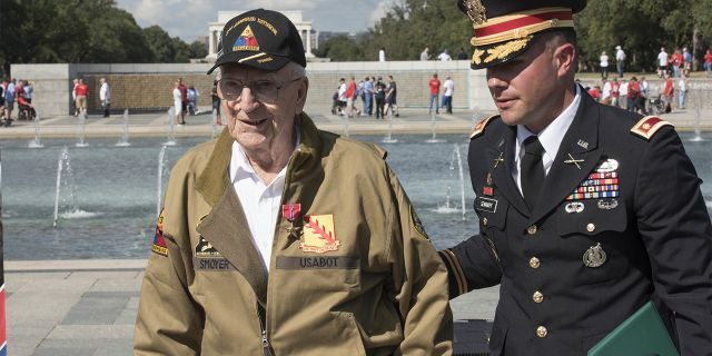 U.S. Army Major Peter Semanoff guides Clarence Smoyer back to his seat after awarding him the Bronze Star at the National WWII Memorial in Washington, D.C. (DoD photo by U.S. Navy Petty Officer 2nd Class James K. Lee)
