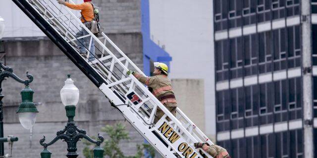A rescued worker, left, and a firefighter look back at the damaged building after a large portion of a hotel under construction suddenly collapsed in New Orleans on Saturday. (Scott Threlkeld/The Advocate via AP)