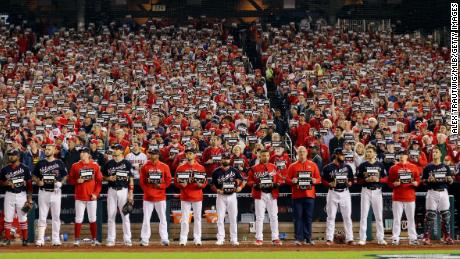 Washington Nationals players stand in front of the dugout with Stand Up 2 Cancer placards during Game 4 of the 2019 World Series.