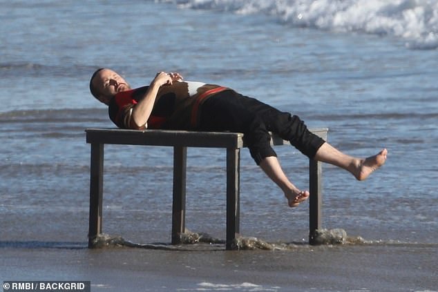 And relax: The film star was spotted reclining on the table as he enjoyed a break