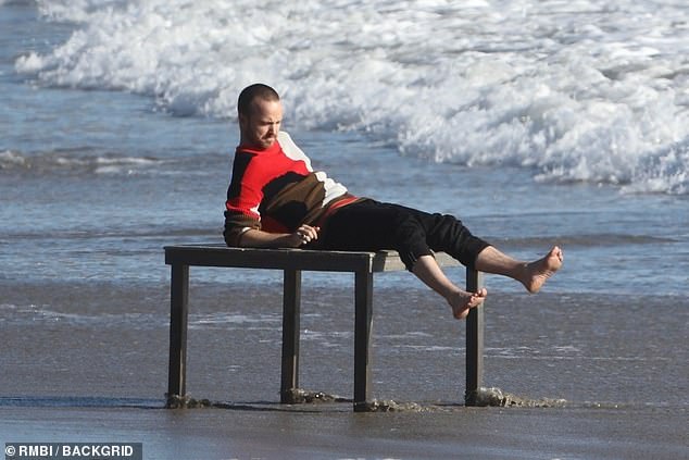 Chill: Aaron took a moment to rest on the table during his beach photoshoot