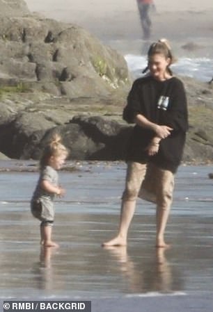 Playful: The duo had fun on the beach as dad worked away