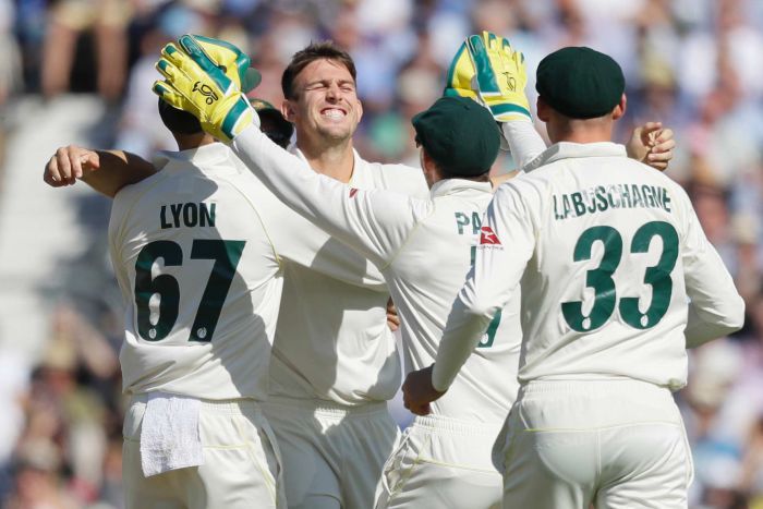 Mitch Marsh smiles widely as he is congratulated by a number of his teammates.