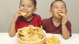 Two boys eating crisps