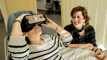 Prince of Wales Hospital is trialing VR therapy to help patients recover.
Pictured is Theodora Michalopoulos wearing a VR headset while former patient Stefanie Ammann looking on.
