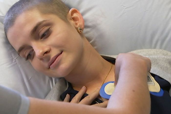 Cancer patient Aliona Grytsenko being fitted with sensors while lying in hospital bed.