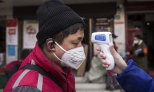 A community worker checks the temperature of courier in an Express station on 29 January in Hubei province.