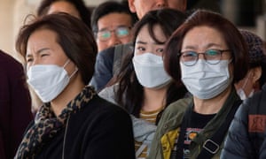 Passengers wear face masks to protect against the spread of the coronavirus as they arrive on a flight from Asia at Los Angeles International Airport.