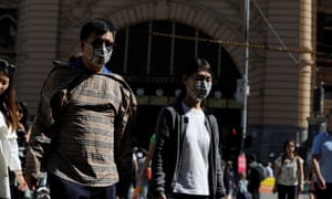 People wearing face masks walk by Flinders Street station in Melbourne after cases of the coronavirus were confirmed in the Australian city on Wednesday.