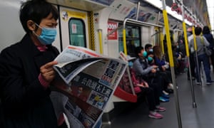 A passenger reads news about a new coronavirus outbreak during a train trip in Hong Kong