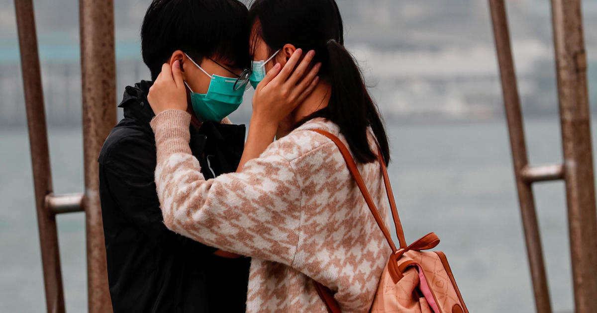 A couple wears masks as the embrace, following the outbreak of the novel coronavirus on Valentine's Day in Hong Kong 