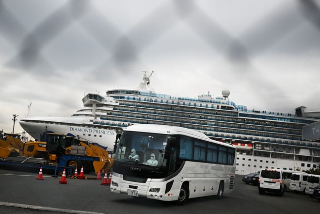 A bus driven by a chauffeur in protective gear departs the dock occupied by the quarantined Diamond Princess.  Eleven passengers who are elderly or have pre-existing medical conditions were removed from the ship Friday and will finish out their quarantine on shore in Japan.