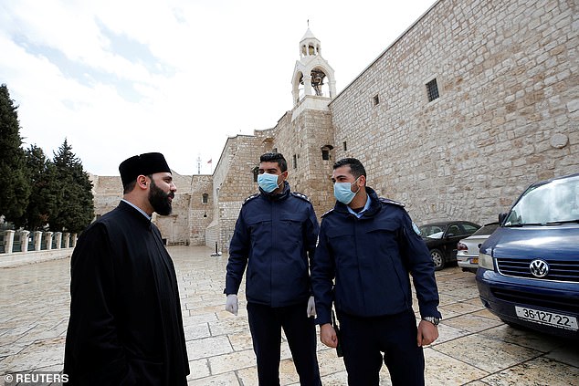 Palestinian police officers stand guard outside the Church of the Nativity that was closed as a preventive measure against the coronavirus in Bethlehem in the Israeli-occupied West Bank
