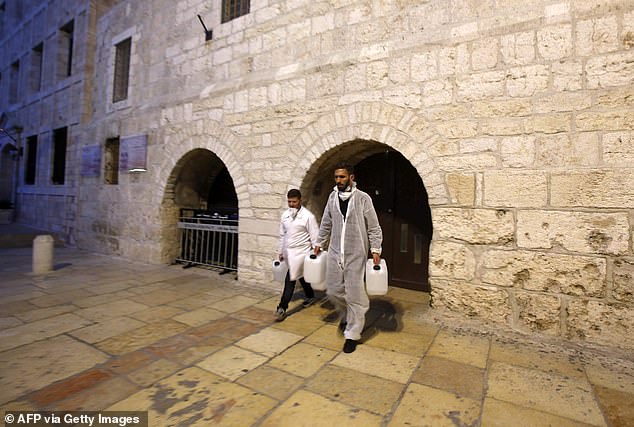 Private health workers walk out of the Church of the Nativity in Bethlehem after spraying sanitizers as a preventive measure against the coronavirus after the church was closed