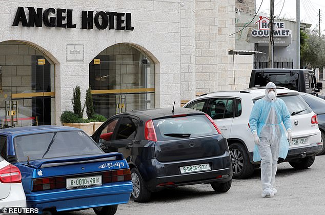 A man in a protective suit walks outside Angel Hotel where, according to a Palestinian government official, a group of American visitors have been quarantined in Beit Jala