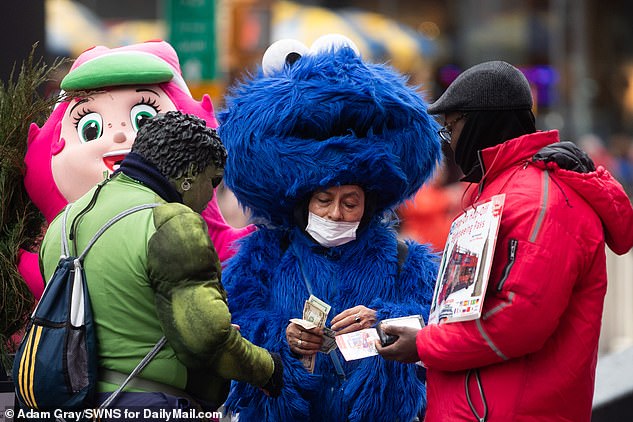 A woman dressed as Cookie Monster from Sesame Street wears a protective mask whilst working in Times Square on Sunday