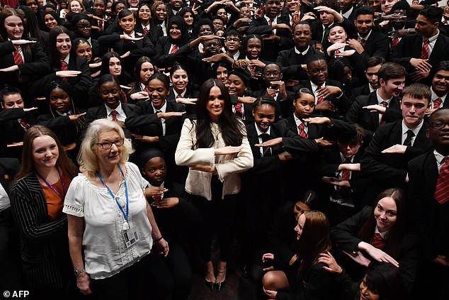 Picture: the Duchess poses with schoolchildren in Essex, making the 'Equality' sign