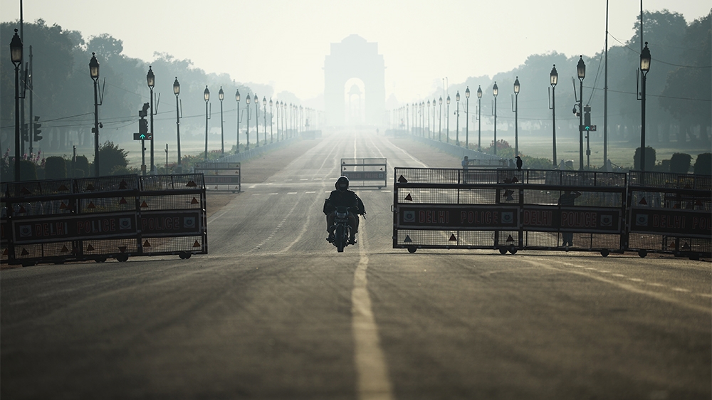 A motorist rides through deserted Rajpath road during a one-day Janata (civil) curfew imposed as a preventive measure against the COVID-19 coronavirus, in New Delhi on March 22, 2020. - Nearly one bil