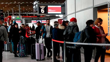 Travellers queue at an airport information desk at Paris-Charles-de-Gaulle airport after a US 30-day ban on travel from Europe.