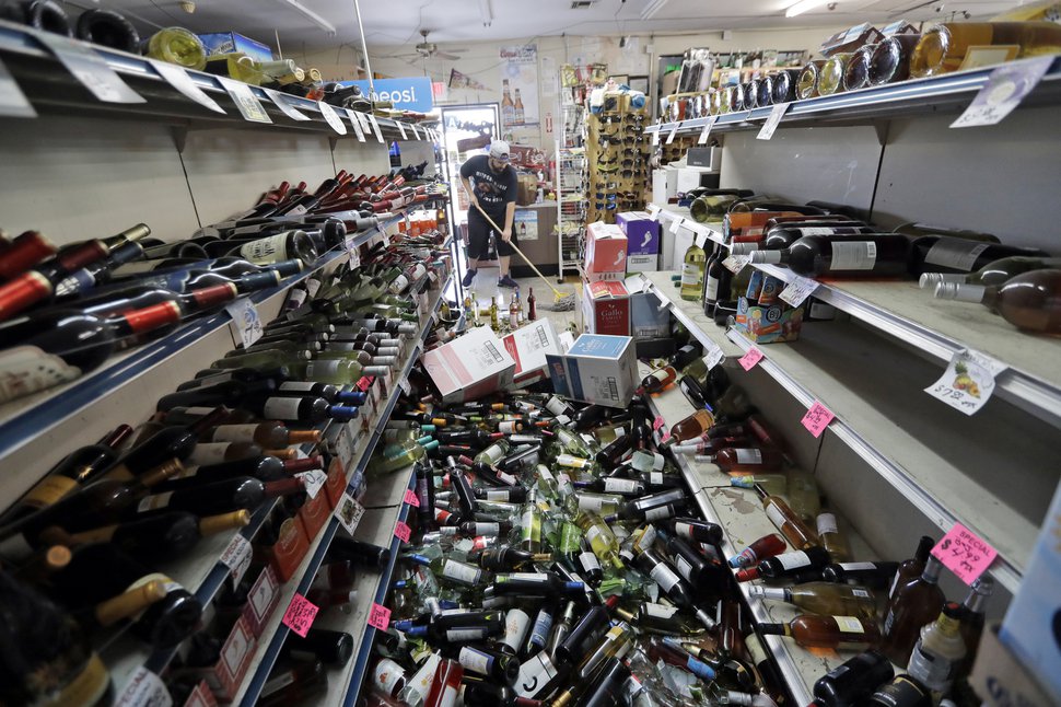 (Marcio Jose Sanchez | The Associated Press) Bottles of wine are strewn in the middle of an aisle as Victor Abdullatif, background center, mops inside of the Eastridge Market, his family's store, Saturday, July 6, 2019, in Ridgecrest, Calif. 