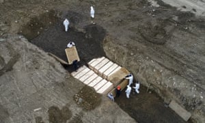 Workers wearing personal protective equipment bury bodies in a trench on Hart Island, Thursday, 9 April 2020, in the Bronx borough of New York.