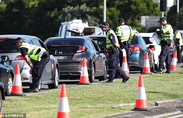 Police officers are seen stopping care at the NSW ansd QLD border after entry was closed for non-permit holders in a bid to restrict travel and slow COVID-19 in it's tracks