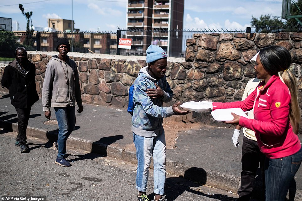 A homeless man gestures as he receives a food parcel during a food distribution by Meals on Wheels in Hillbrow, Johannesburg