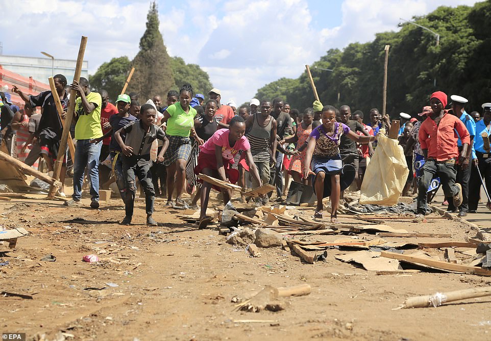 Residents pick up remains from destroyed vending market stalls in the township of Mbare, Zimbabwe, on Saturday afternoon