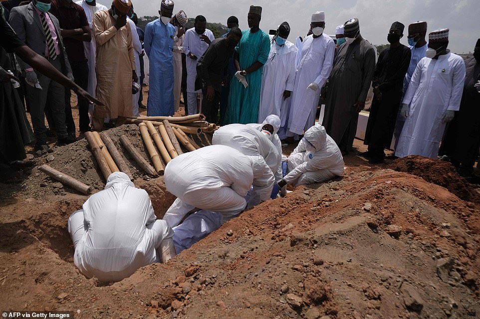 Health workers lower the remains of Nigeria's Chief of Staff (COS), Abba Kyari, into a grave at the Gudu Cemetery in Abuja on Saturday