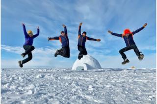 Justin Rowlatt (right) jumping with colleagues and a scientist in Antarctica