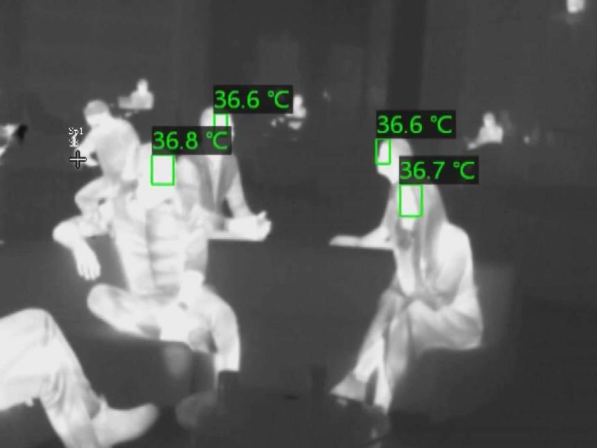 Black and white thermal imaging of people showing their temperatures