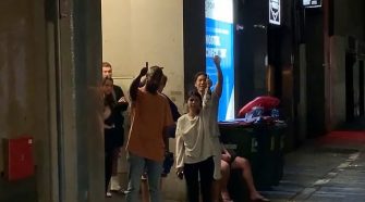 A group of young backpackers were seen ignoring social distancing rules as they gathered outside their hostel in Sydney