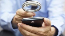 Businessman using mobile smart phone with magnifying glass