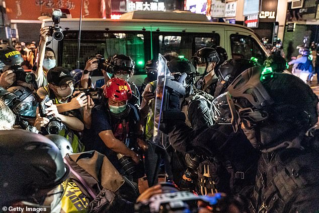 Riot police hold back members of media during a demonstration in Mongkok district
