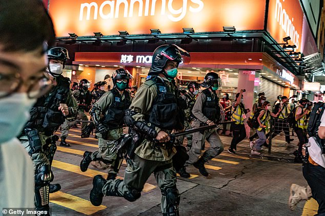 Riot police wearing protective masks charge on a street during a demonstration in Mongkok district on Sunday
