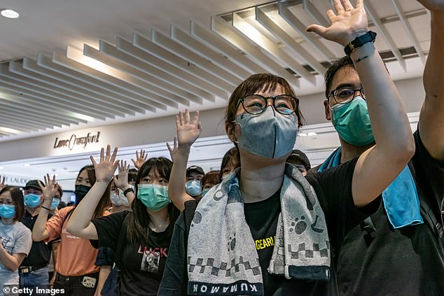 Anti-government protesters wearing protective masks sing songs and make gestures during a demonstration at a shopping mall on May 10