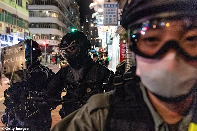 Riot police wearing protective masks charge on a street during a demonstration in Mongkok district on May 10