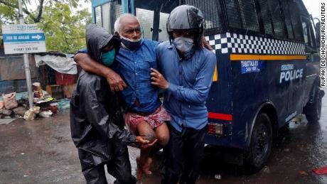 Police officers carry a disabled man to a safer place following his evacuation from a slum area in Kolkata, India.